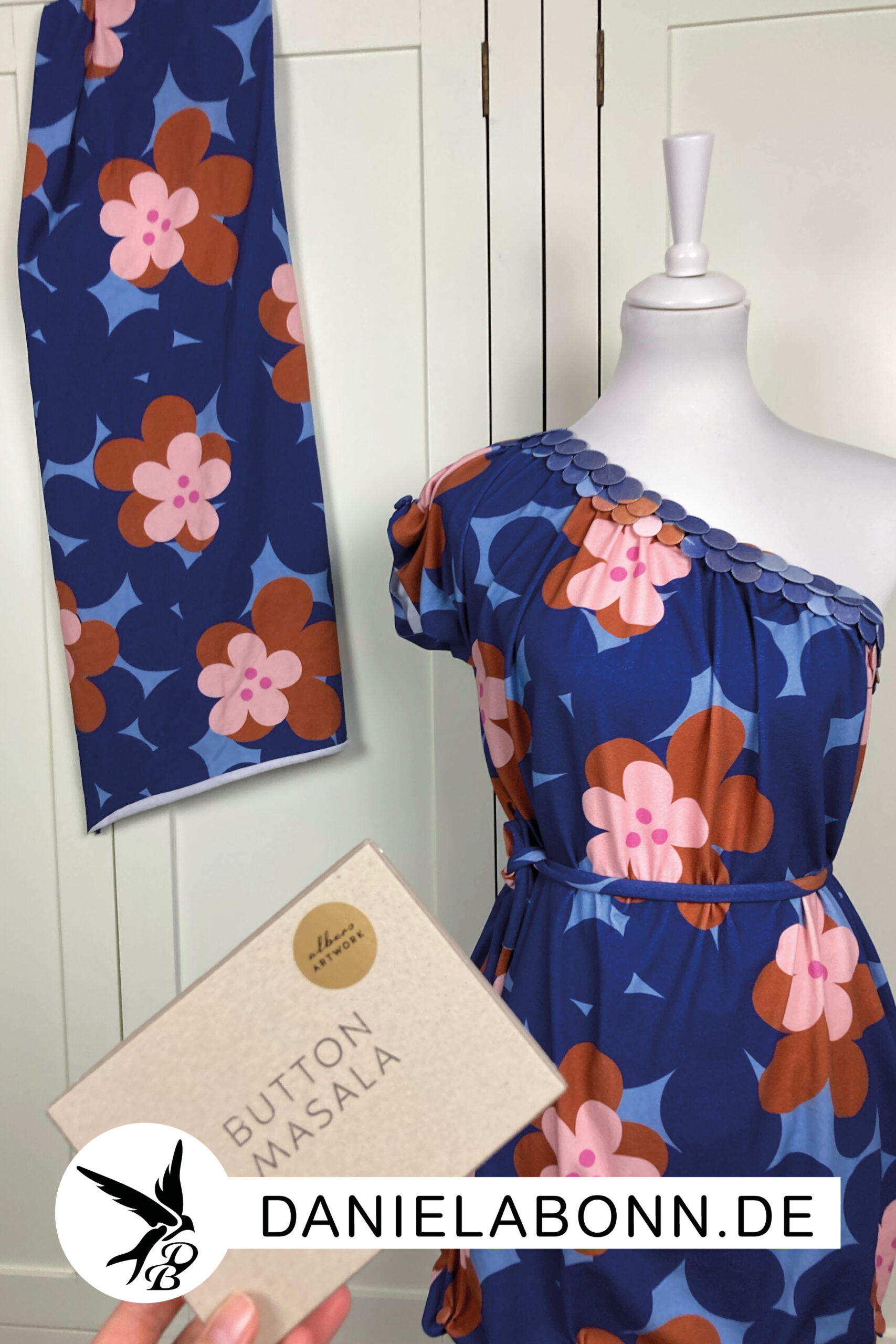 Stoff aus der Stoffkollektion Button Loop mit großen Blumen als Motiv in den Farben Blau und Kupfer/ Braun. Stoffe wurden mit Hilfe der Button Masala Technik zu einem Kleid mit einem asymmetrischen Ausschnitt geknöpft
